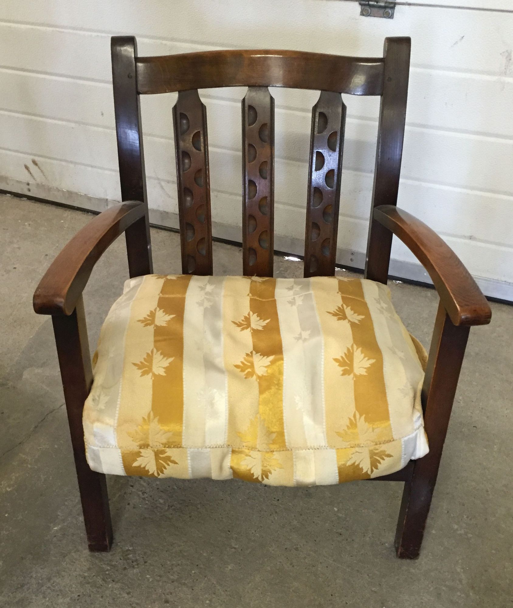 An Arts & Crafts style nursing chair with a gold/cream cushion.