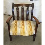 An Arts & Crafts style nursing chair with a gold/cream cushion.