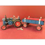 A wind-up tinplate blue tractor and trailer, in working order