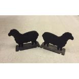 A pair of black cast iron doorstops in the shape of sheep.