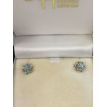 A pair of 9ct gold stud earrings set with blue topaz stones and central diamonds.