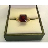 Hallmarked 9ct gold dress ring set with a large square cut garnet with diamond set shoulders - one