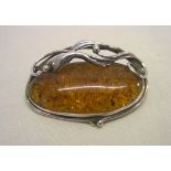 Art Nouveau design hallmarked silver and amber brooch. Measures 4.5cm across.
