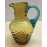 An amber glass jug with a blue twist design glass handle