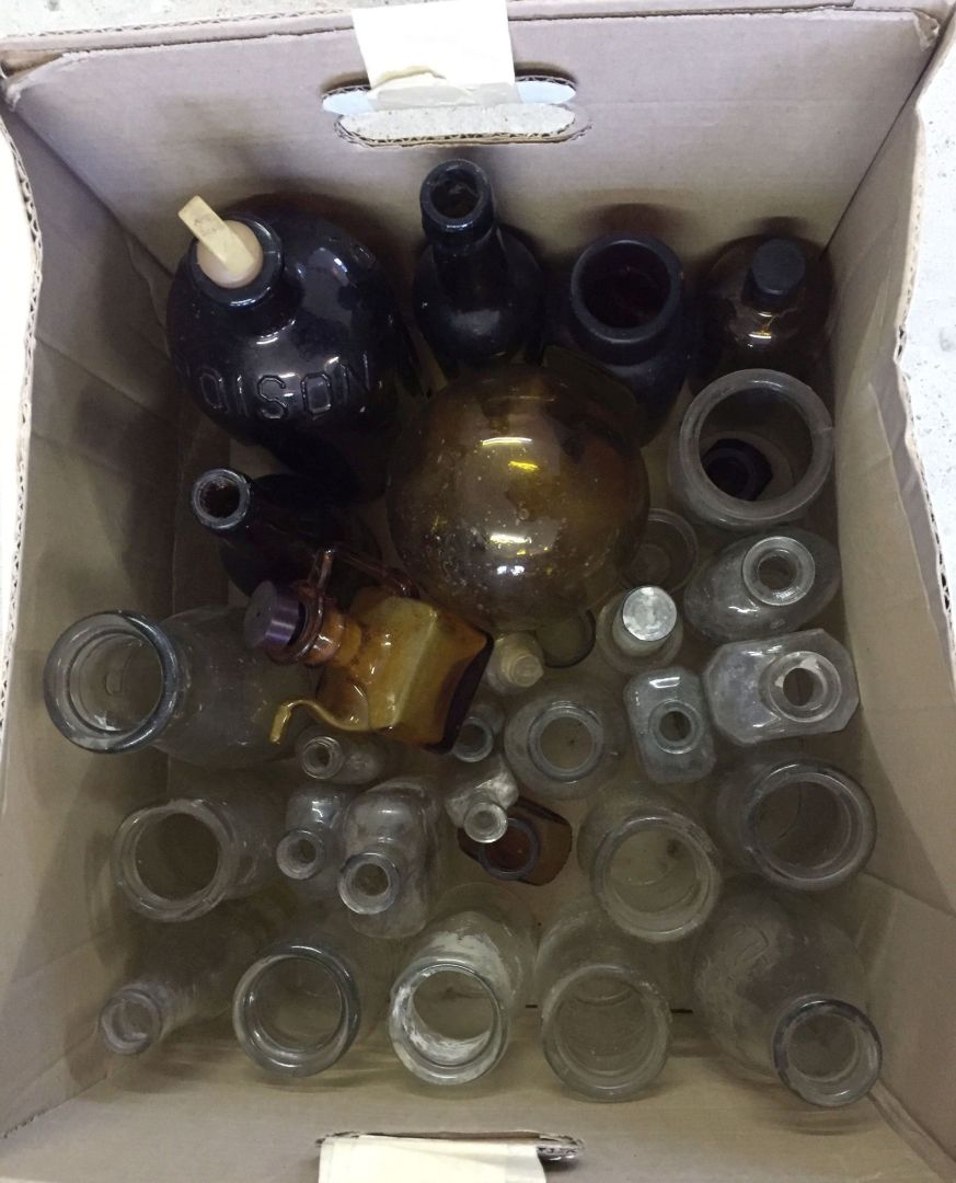 A box of clear and brown glass bottles to include vintage milk bottles.