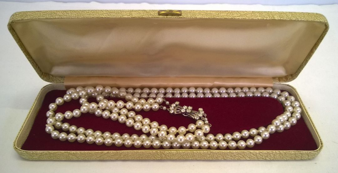 A double string of vintage simulated pearls with diamante clasp in c1950s case.