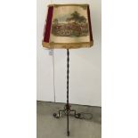 A wrought iron lampstand with shade depicting hunting scenes