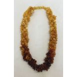 An Amber necklace, 16 inches long comprising 3 twisted strings of graduated colour amber chips