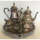 A silver plated tea set on a footed tray, together with a silver plate ornately decorated cream jug