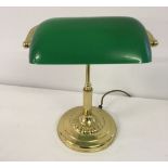 A reproduction brass desk lamp with green glass shade.