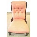 A Victorian nursing chair with turned legs, china casters & pink upholstery.