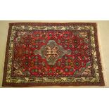 A vintage wool rug in red with pale blue central geometric design. 147 x 102cm