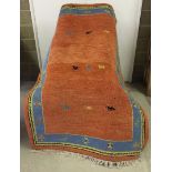 A hand woven rug of red/orange & blue colouration.