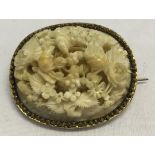 An ornate antique ivory carved brooch of field mice and flowers. 4 x 3.5cm