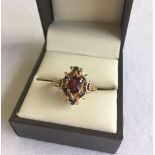 A pretty gold dress ring set with a central garnet and small sapphires. Total weight approx 4g.