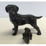 2 black Labrador figurines; 1) ceramic approx 19cm long 2) resin puppy with boot approx 9cm long.