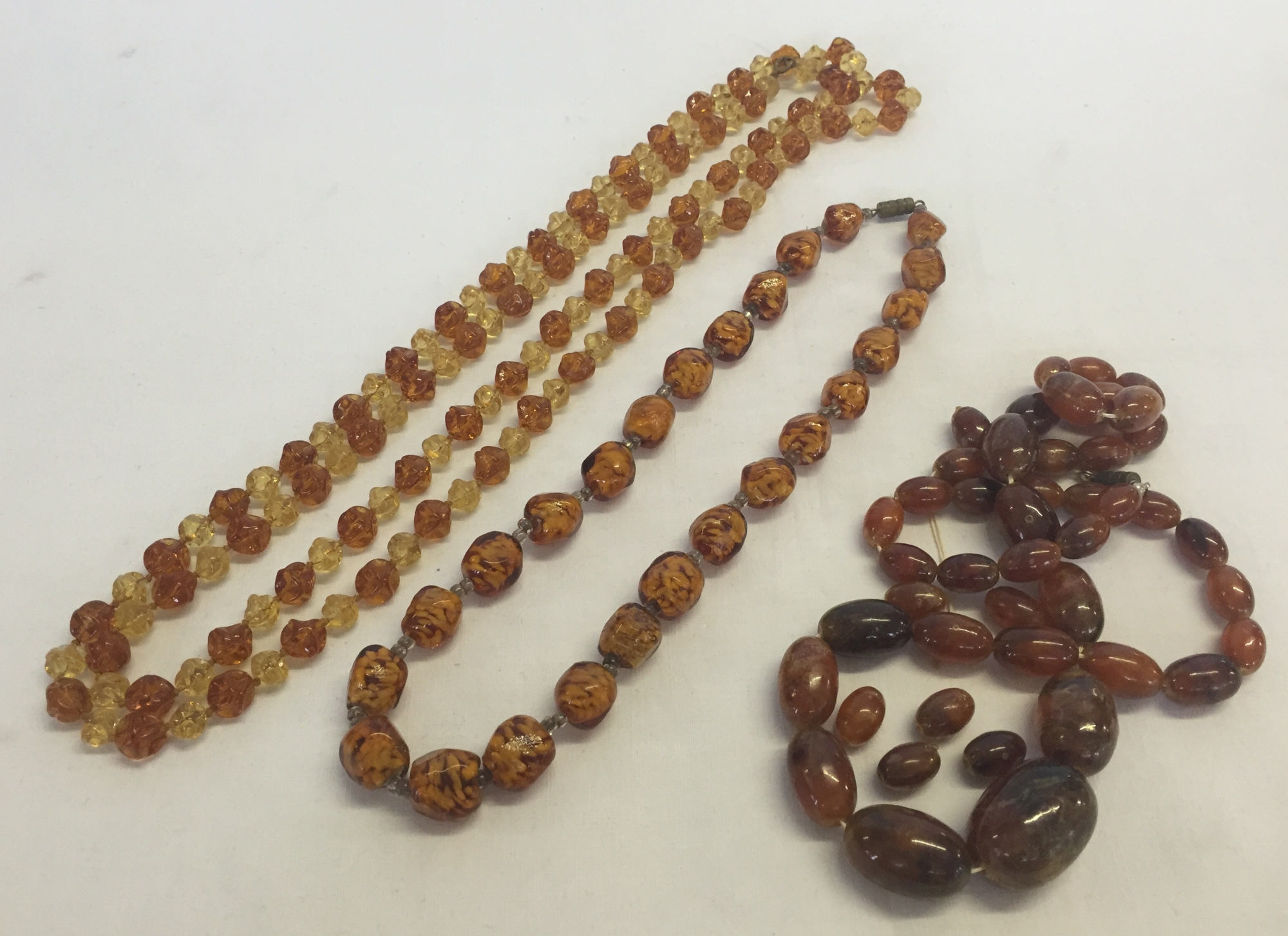 3 vintage amber coloured necklaces, 2 glass and one c1930s plastic/bakelite (needs re-stringing).