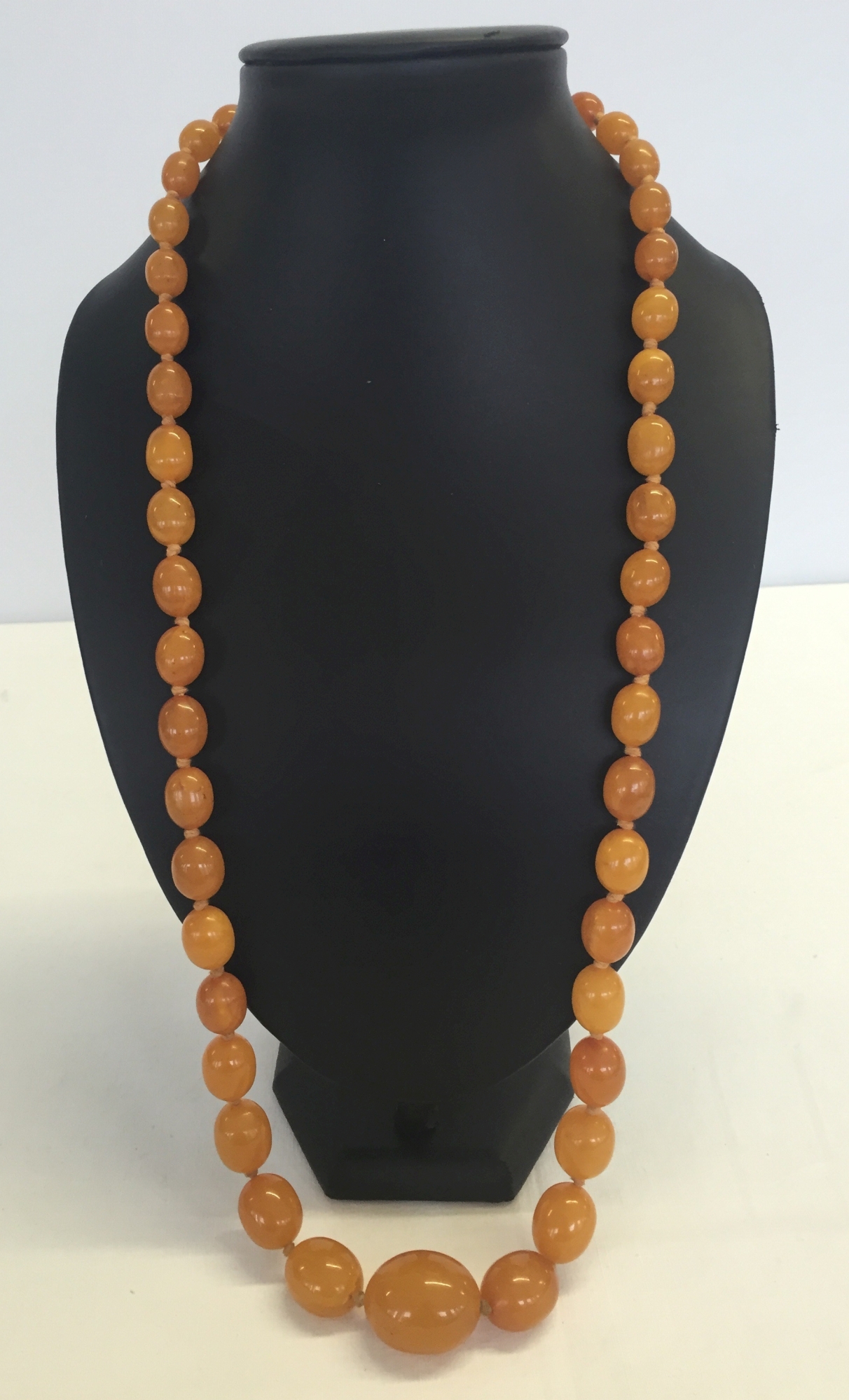 A c1920s pressed amber necklace. Comprising 47 beads sized 3cm to 1.1cm in length. Total approx