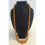 A c1920s pressed amber necklace. Comprising 47 beads sized 3cm to 1.1cm in length. Total approx