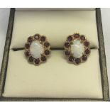 A pair of 9ct gold opal & garnet earrings. Central oval opals surrounded by a ring of garnets.