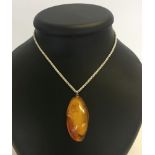 A natural untreated, polished amber pendant 4.5cm long. Approx weight 8g. On a white metal chain.