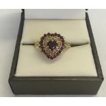 A 9ct gold heart shaped dress ring, Central heart shaped garnet surrounded by gold scroll work and