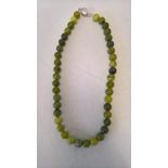 A necklace strung with round polished serpentine beads. Clasp marked 925. Length approx 18 inches.