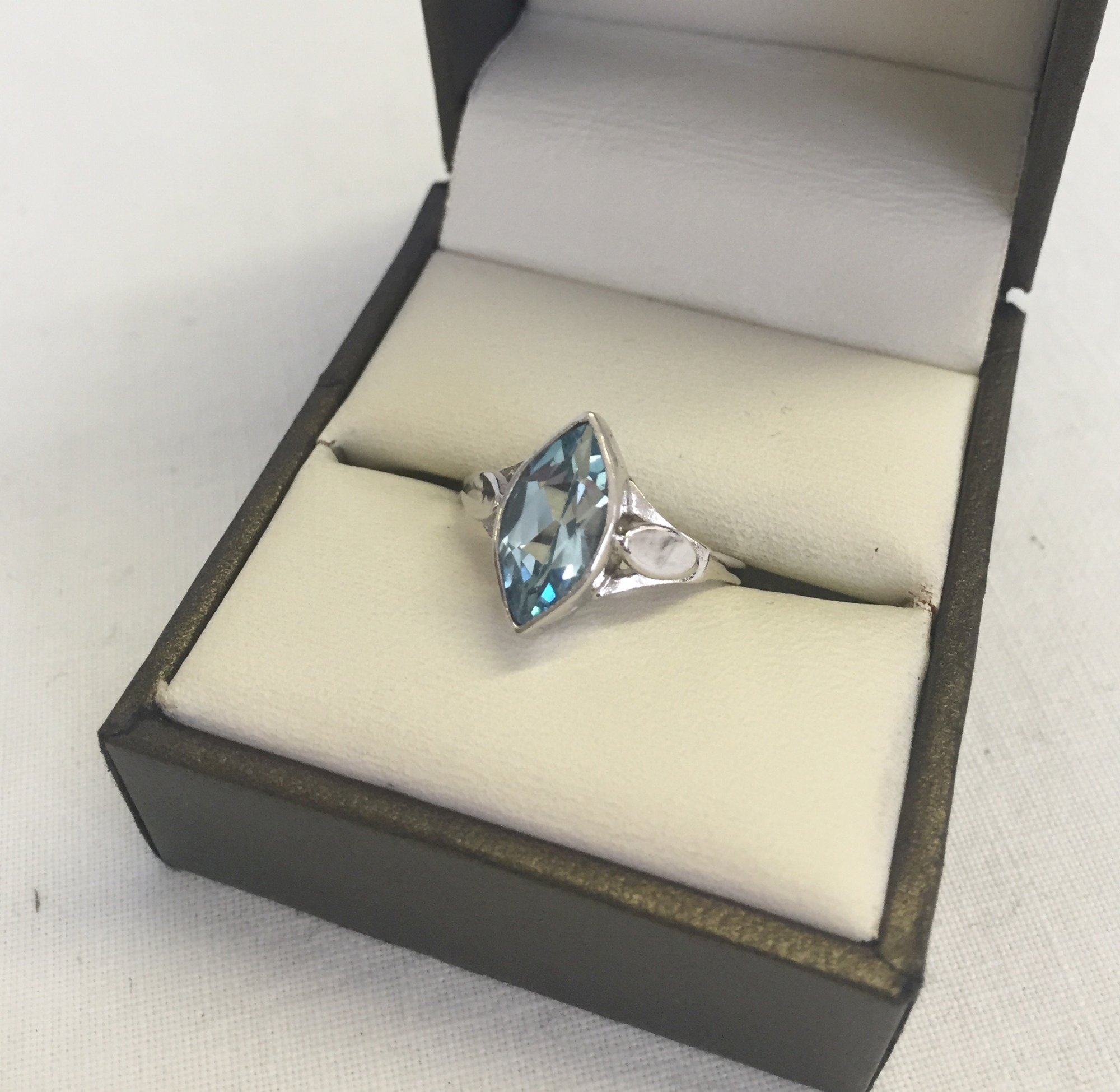 A 9ct white gold dress ring set with a marquise cut blue topaz. Decorative shoulders size N1/2