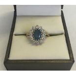 A 9ct gold ring set with a central oval blue topaz stone surrounded by CZ stones. Size L 1/2.