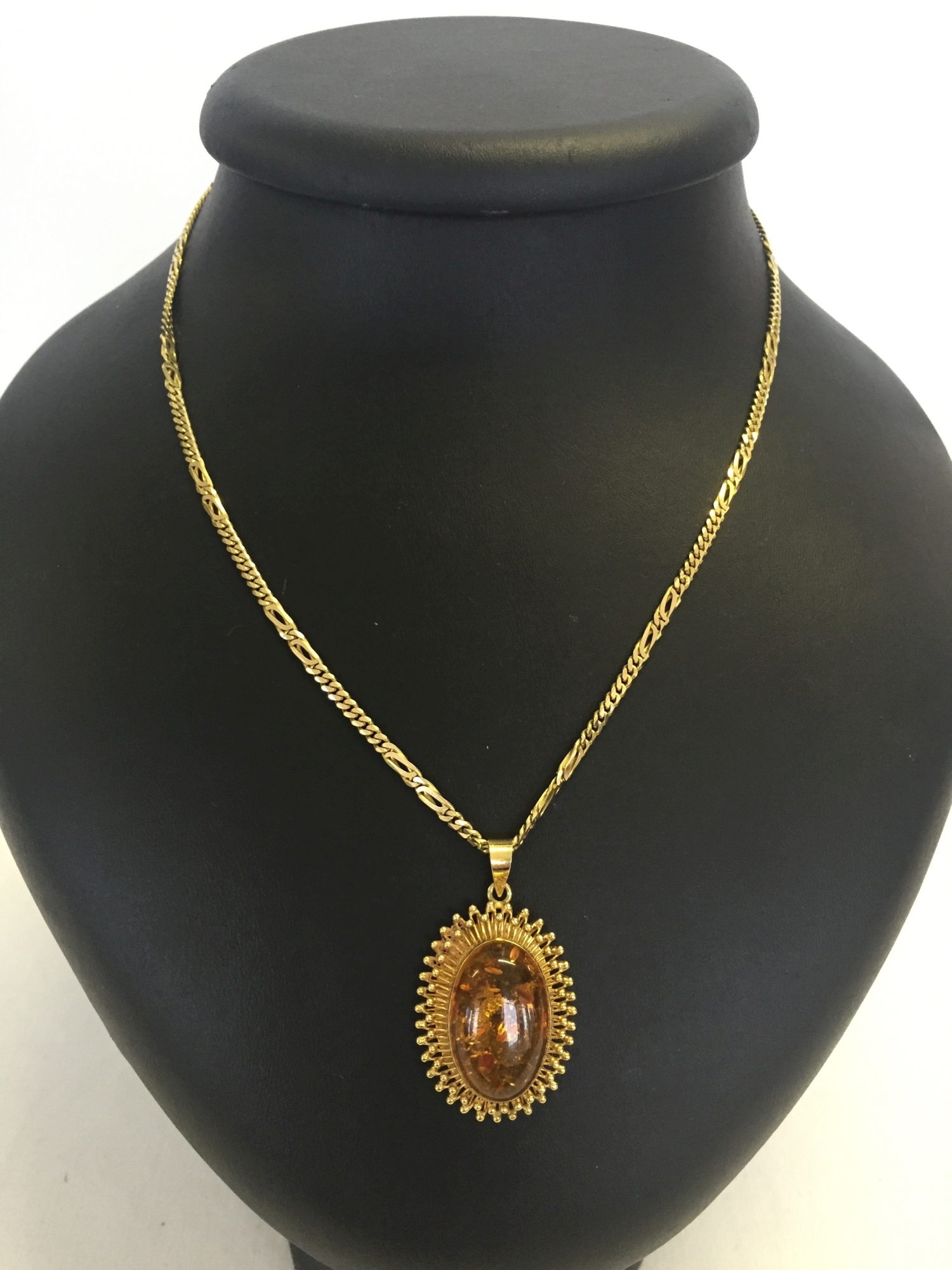 A Copal modern amber oval pendant set in ornate 18ct gold mount on a 14ct gold chain. Total weight