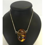 A large Baltic amber egg pendant on a sterling silver chain. Measures 4.5cm x 3cm. Weight of amber