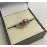 A 9ct gold dress ring in a twist design set with 3 rubies and 6 small diamonds. Size M1/2 total