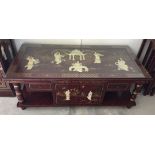 A Chinese red lacquer coffee table with storage & glass top with applied mother of pearl figures and