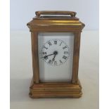 A miniature brass carriage clock with bevel edge glass panels and enamel face. Approx 8cm high.