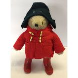 An 18" Gabrielle Designs Paddington Bear wearing red boots, red felt duffle coat aand dark blue.