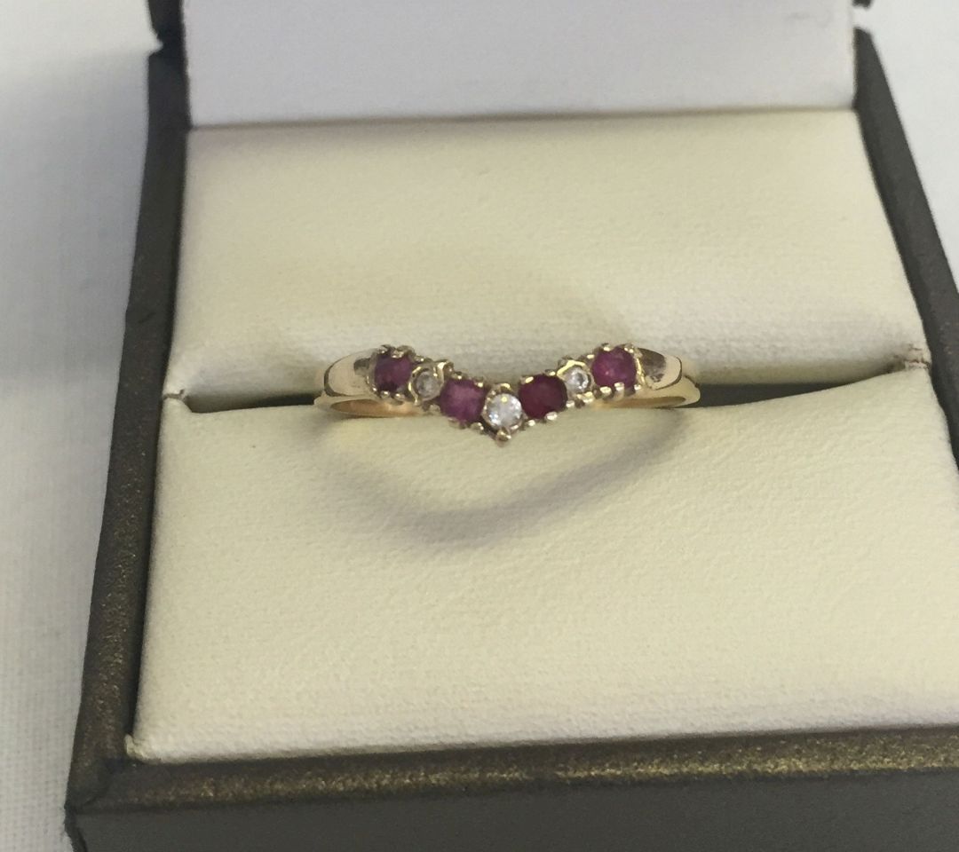 A 9ct gold wishbone dress ring set with 4 rubies and 3 cubic zirconias. Size P total weight 1.1g.