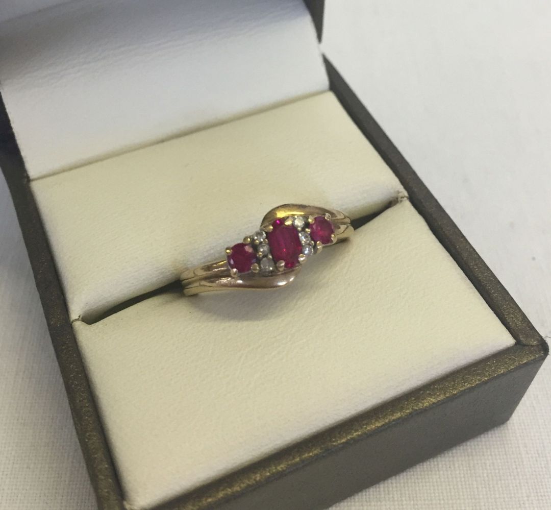 A 9ct gold dress ring in a twist design set with 3 rubies and 6 small diamonds. Size M1/2 total