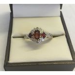 A 9ct gold dress ring set with garnets and diamonds. Central oval garnet with two smaller garnets