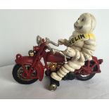 A cast iron reproduction Michelin Man on a motorcycle figure.