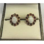 A pair of 9ct gold opal & garnet earrings. Central oval opals surrounded by a ring of garnets.