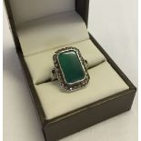 A 925 marcasite and silver ring set with a large green stone. Size M. 1 small piece dislodged on