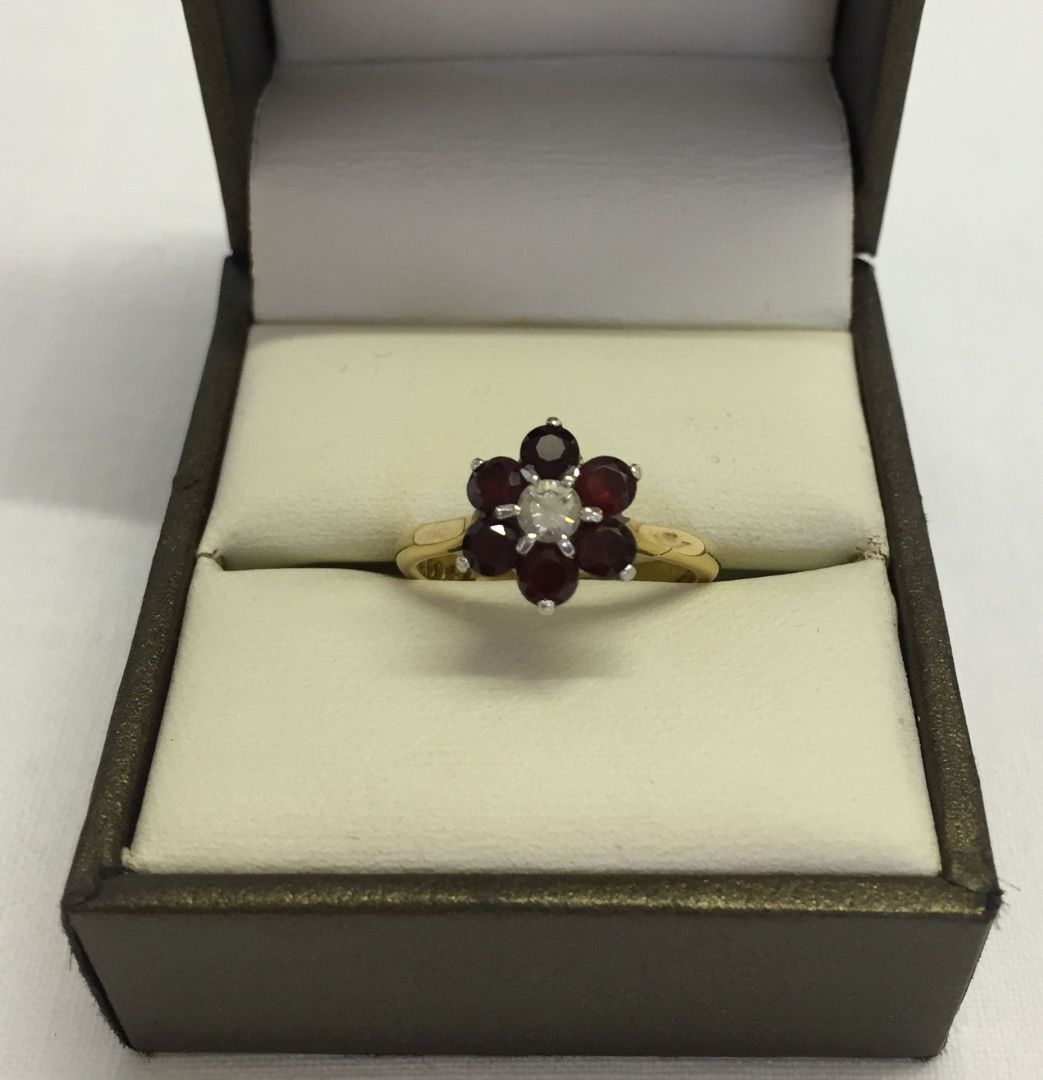 A boxed 18ct gold diamond and garnet cluster ring. Central diamond (approx .15ct) surrounded by 6