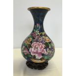 A Chinese cloisonne vase on wooden stand. Flower decoration on vase. Vase 22.5cm tall (excluding