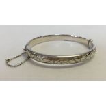 A silver bangle with engraved decoration and safety chain, hallmarked Birmingham 1970 total weight