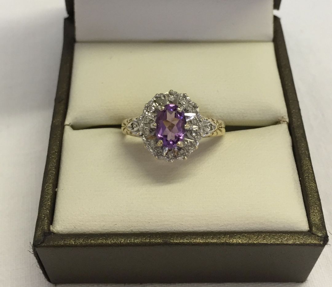 9ct gold ladies dress ring set with central oval amethyst surrounded by small diamonds. Size