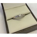 A 9ct white gold and diamond ring, size K1/2. Central illusion set diamond with a row of baguette,