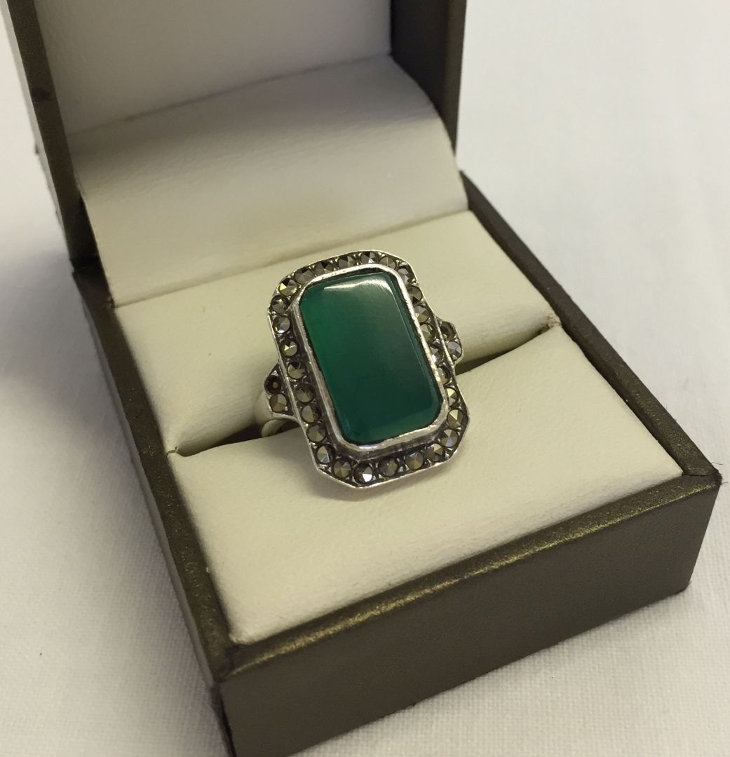 A 925 marcasite and silver ring set with a large green stone. Size M. 1 small piece dislodged on