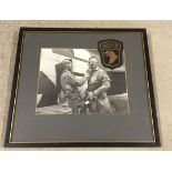 A framed and glazed original photograph and badge from the American Airborne regiment "Screaming