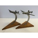 2 metal aeroplane ornaments on wooden plinths.