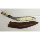 A bone handled Kukri with decoration to blade, in a leather sheath.